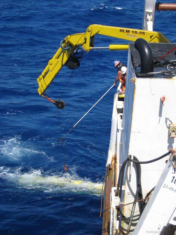 Crew using a boat hook to grab a tag-line attached to the SM30 sonar towfish.